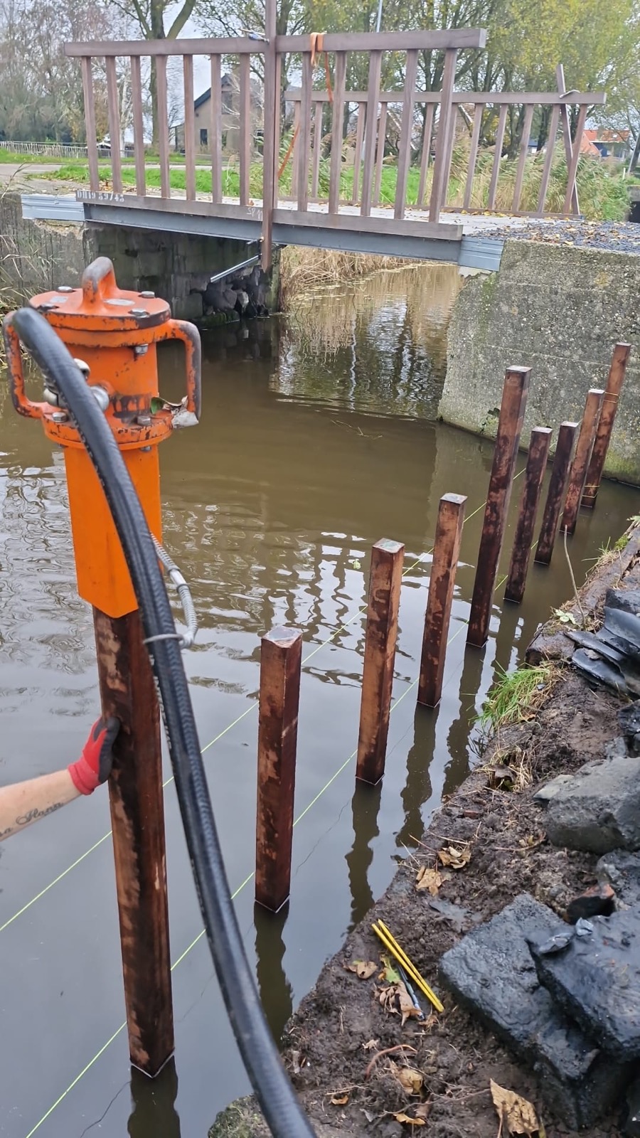 Palen worden geheien voor een beschoeiing langs het water